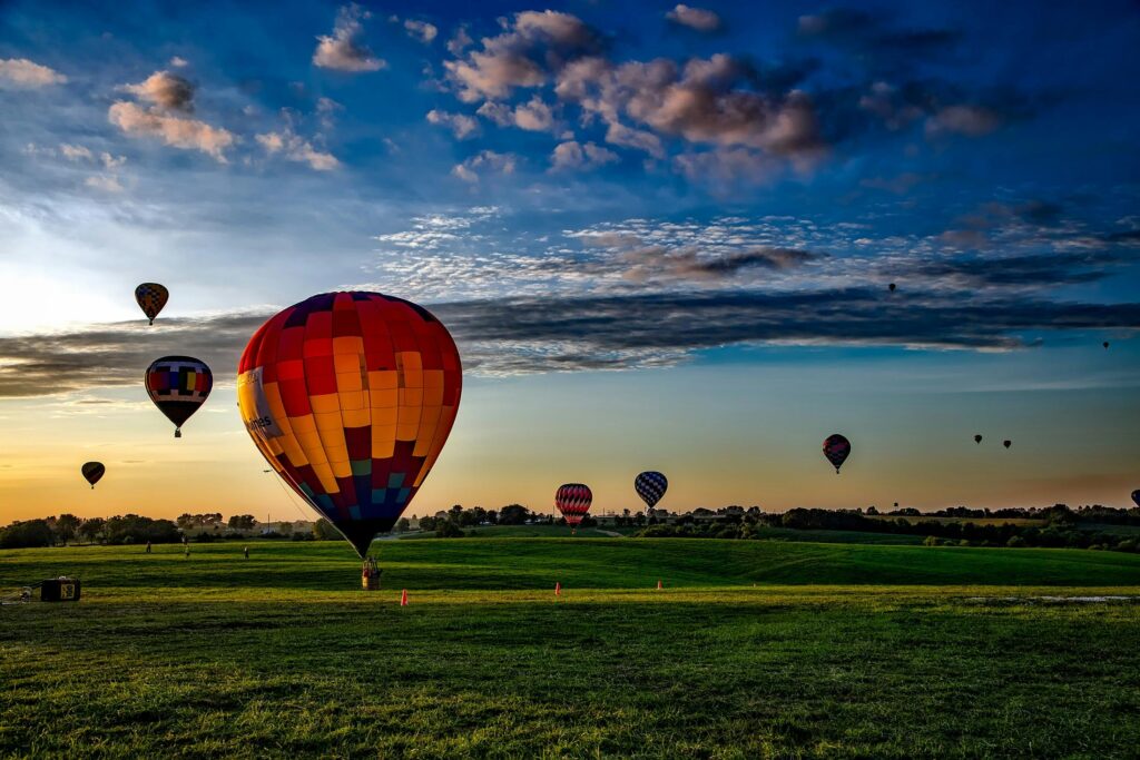 pexels-photo-210012-210012 Vibrant hot air balloons take off at dawn over a rural field, showcasing a picturesque landscape.