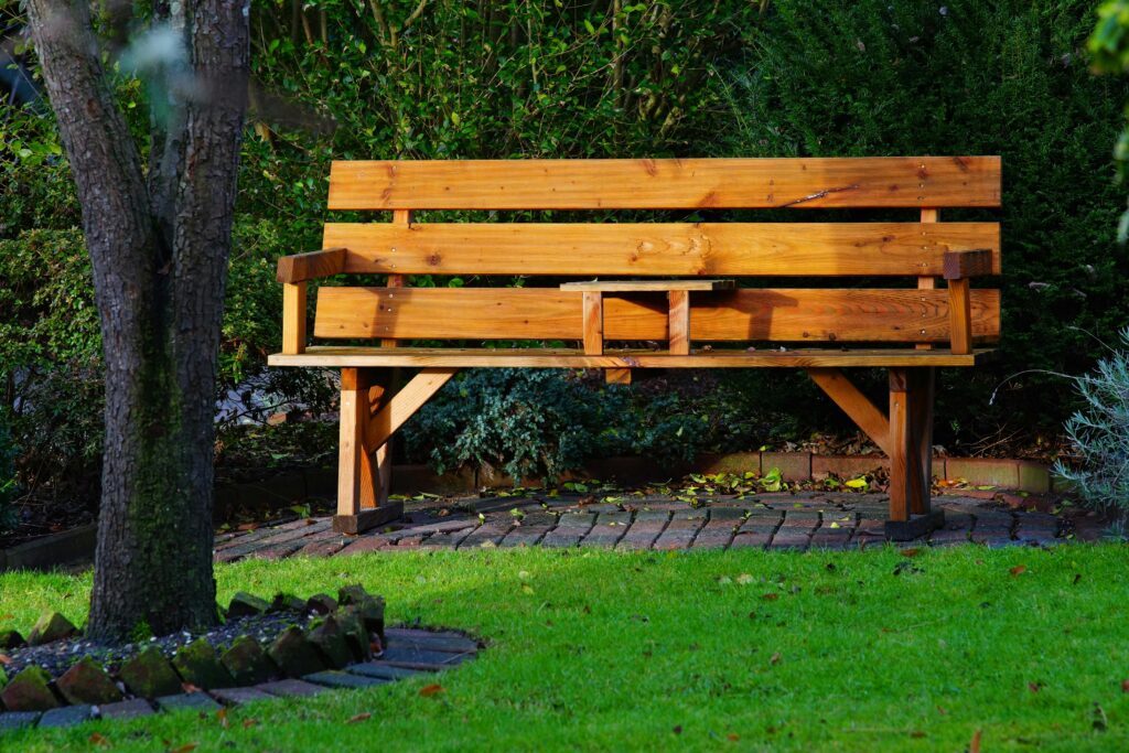 A serene wooden bench in a leafy, sunlit garden perfect for relaxation and solitude.